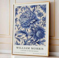 a blue and white floral print is on the wall next to a framed poster that reads william morris