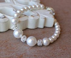 a close up of a bracelet with pearls and diamonds on the clasp, next to a pair of shoes