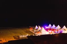 tents are lit up at night on the beach