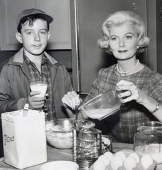 an old black and white photo of two people at a table with eggs in bowls