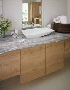 a bathroom with a sink, mirror and wooden cabinetry on the counter top in front of it