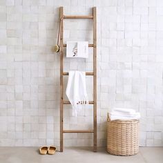 a bathroom with white tiles and a wooden ladder leaning against the wall next to a towel rack