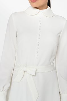 "A collared midi dress featuring a button front closure (imitation), fabric belt, and a fit and flare silhouette. - fit and flare silhouette - high rounded collar - knee length (midi) - long sleeves with cuffs - fabric belt - covered button front decor - concealed zipper closure - lined bodice and skirt - color: white Fiber: 60% viscose, 35% polyester, 5 % elastane, Lining - 95 % viscose, 5% elastane. For size S:dress length- 40,0 \" (102 cm), sleeve length 24,21\" (61,5 cm) Our model wears size Elegant Long Sleeve Belted Midi Dress, Cream Midi Dress For Wedding Guest, Classic A-line Midi Dress For Wedding, Elegant A-line Dress With Covered Buttons, Spring Wedding Dress With Buttons, Feminine Long Sleeve Midi Dress With Button Closure, Elegant Belted Midi Dress With Button Closure, Belted Midi Dress For Wedding, Belted Maxi Dress For Wedding