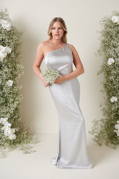 a woman in a white dress holding a bouquet of flowers and posing for the camera