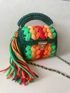 a handbag with multicolored handles and tassels on the handle is sitting on a white surface