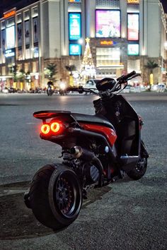 the motorcycle is parked on the side of the road in front of an illuminated building