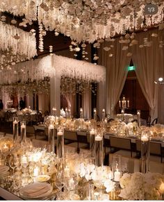 the tables are set with white flowers and candles for an elegant wedding reception at night