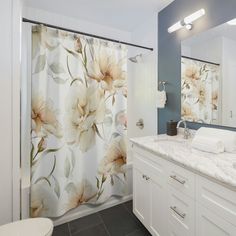 a bathroom with a floral shower curtain next to a white toilet and sink in front of a mirror