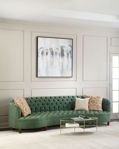 a living room with white walls and green couches in front of a painting on the wall