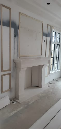 an empty room with white walls and fireplace in the middle, surrounded by construction materials