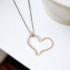 Indulge in the timeless elegance of our Open Heart Necklace. The delicate sterling silver chain is home to a handcrafted gold open heart charm, adorned with shimmering silver beads. Exquisitely combining luxury and sophistication, this necklace is a must-have for any wardrobe. Sterling Silver Chain Adjustable Lenth from 15" - 18" Handmade 14k Gold Filled Open Heart Charm Sent in a Ribboned Gift Box with Polishing Cloth Handmade in Montana Elegant Everyday Jewelry With Heart Beads, Gold Heart Necklace With Box Chain, Heart Charm Pendant Necklace For Everyday, Everyday Heart Charm Pendant Necklace, Delicate Heart Pendant Necklace With Heart Beads, Minimalist Sterling Silver Jewelry With Heart Beads, Delicate Heart Pendant Charm Necklace With Heart Beads, Delicate Open Heart Jewelry With Delicate Chain, Delicate Heart Bead Charm Necklace With Heart Pendant