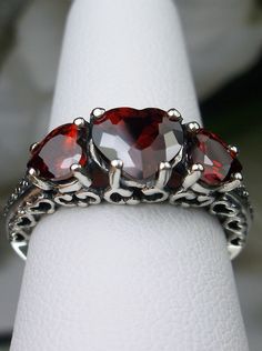 "Red Garnet Cubic Zirconia Ring Description Hearts Design#143 Made To Order This is a lovely Edwardian inspired ring in solid sterling silver. The gorgeous filigree ring is set with 3 heart cut simulated/Man-made garnet red CZ gemstones. The 2 smaller gems are 5mm in diameter, and the center one is 7mm in diameter. Notice the amazing etched band... The ring sits 1/4th\" (7mm) off the finger. The quality of the silver and gemstones are simply breathtaking... a ring that will last for countless ye Red Heart-shaped Cubic Zirconia Jewelry, Dazzling Three Stone Jewelry Gift, Heart-shaped Ruby Jewelry For Wedding, Heart-shaped Ruby Wedding Jewelry, Red Heart Shaped Rings With Accent Stones, Red Heart-shaped Rings With Accent Stones, Red Heart Cut Jewelry For Anniversary, Red Heart-cut Jewelry For Anniversary, Red Garnet Round Cut Jewelry