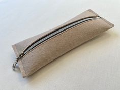 "Made with love from the San Francisco Bay Area! This handmade makeup bag is made from a single piece of thick (2mm), high-quality felt that keeps its shape even with daily use. The pouch is a beige wheat color, secured with a smooth zipper made from silver hardware and contrasting gray trim. An elegant accessory perfect for minimalists. The pouch can be used to hold makeup, brushes, pencils/pens, or other small items. Perfect for people on the go, students, artists, minimalists or anyone who ne Beige Zipper Pouch Pencil Case For Daily Use, Everyday Rectangular Pencil Case With Zipper Pocket, Beige Zipper Pencil Case For Daily Use, Everyday Rectangular Pencil Case With Zipper, Minimalist Rectangular Pouch With Zipper, Minimalist Rectangular Zipper Pouch, Modern Rectangular Pencil Case For Everyday Use, Beige Zipper Pouch Pencil Case For Personal Use, Everyday Beige Rectangular Pencil Case