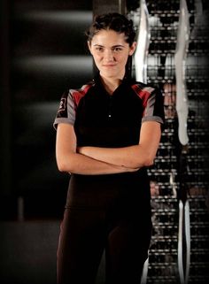 a woman standing with her arms crossed in front of a rack of computer equipment,