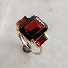 ITEM DESCRIPTION: --> The ring is made from Solid 14K Yellow Gold. Gemstone used is absolutely natural and ethically sourced.  --> Natural Garnet  in octagon and baugette shape and prong setting are studded on it with utmost precision.   Gemstone: Garnet Gem size: 10x12mm octagon (1pcs) Gemstone: Garnet Gem size : 3x6mm baugette (2pcs) Total Gem weight: 7.30 carats Gold purity: 14K (58.33% approx.) Gold weight: 2.16 grams  Gross weight of ring: 3.62 grams >>The Gold purity is guaranteed and it comes with authentic 14K gold hallmark. >>Since these Rings are handmade, they are Nickel/Lead FREE.  CUSTOMISATION: >>Size Customization is available for this ring and it is available in all ring sizes. >>Gemstone customization is also available and the main gemstone can be substituted with a gem of Luxury Garnet Rings With Accent Stones, Formal Garnet Rings Fine Jewelry, Elegant Formal 14k Gold Ruby Ring, Elegant Cluster Ring With Gemstone Accents For Anniversary, Formal Garnet Gemstone Cluster Ring, Elegant Ruby Ring With Baguette Cut And Accent Stones, Elegant 14k Gold Ruby Ring, Elegant Anniversary Cluster Ring With Gemstone Accents, Elegant Emerald-cut Ruby Ring