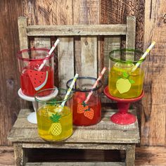 three glasses with strawberries and pineapples are sitting on a small wooden table