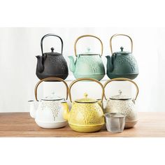 four tea kettles are stacked on top of each other in different colors and designs