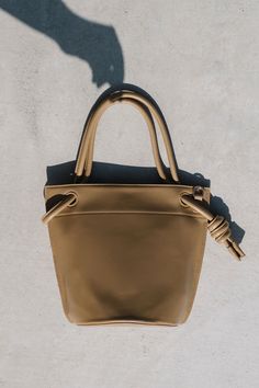 Dress up or keep it casual with the Miriam crossbody bucket bag. Designed with a handle that knots at the side of the opening. The interior features a slot and zip pocket to keep your belongings neatly organized and secured. Includes an adjustable and removable crossbody strap. Bucket Satchel With Top Carry Handle For On-the-go, Brown Bucket Bag With Adjustable Handle For Everyday Use, Travel Bucket Bag With Adjustable Top Handle, Travel Bucket Bag With Adjustable Handle, Travel Bucket Box Bag With Detachable Handle, Shopping Shoulder Bucket Bag With Adjustable Handle, Adjustable Handle Shoulder Bucket Bag For Shopping, Adjustable Handle Bucket Bag For Shopping, On-the-go Crossbody Bucket Bag With Detachable Handle