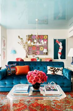 a living room with blue couches and red flowers on the coffee table in front of it