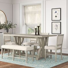 a dining room table with four chairs and a bench in front of the mirror on the wall