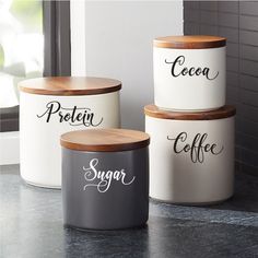 three canisters with the words sugar, flour, and tea on them sitting next to a window