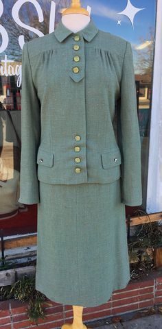 "This 1940's light green skirt set is in incredible condition and would make a great addition to every closet! The jacket is a boxy cut with two small pockets and decorative square buttons. There is no material information available, but my best guess is that the set is made from a thick cotton blend, it feels like a lightweight twill. Both the skirt and jacket are lined in an orange washed silk. The skirt's waist has been altered, it currently measures at 25\", and a metal zipper was added (see photos).  There are no tags on the skirt; the jacket has three tags (please see photos). Please note that the rhinestone detail on the right pocket is missing two stones (see photo).  Features: -Square Buttons -Two Small Jacket Pockets -Rhinestone Detail on Jacket Pockets -Slit in Cuff -Small Shoul Classic Fitted Green Skirt Suit, Classic Green Fitted Skirt Suit, Elegant Green Skirt Suit For Fall, Tailored Green Skirt Suit For Office, Green Tailored Skirt Suit For Office, Vintage Skirt Suit With Buttons For Office, Vintage Office Skirt Suit With Buttons, Classic Green Skirt Suit For Work, Vintage Skirt Suit With Button Closure For Formal Occasions