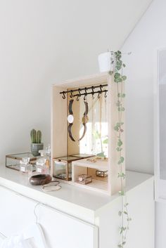 a white dresser with an open drawer and mirror on the top, next to a potted plant