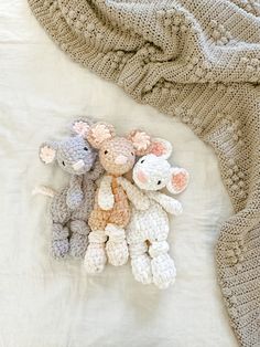 three crocheted stuffed animals laying on top of a white blanket next to each other