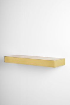 a gold shelf against a white wall with no one in the room to see it