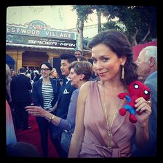 a woman in a pink dress holding a spiderman stuffed animal at the hollywood awards