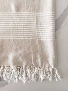 a white and beige striped towel on a marble counter top with the edge of it folded up