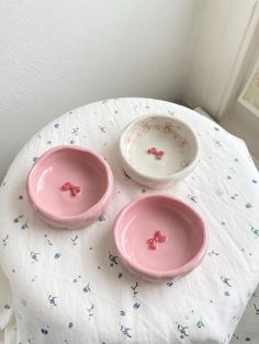 three pink bowls sitting on top of a white table