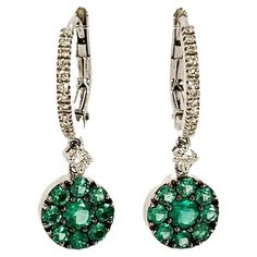 Gorgeous pair of 18kt white gold, Diamonds and Emeralds dangle earrings. This model is made by a hoop top with Diamonds and lever closure. The dangling part of the earring is composed of a round white gold tablet, embellished with multiple Colombian emeralds arranged concentrically. The two parts are joined by a larger Diamond that creates movement and brightness also, thanks to the burnished griffes, the color of the Emeralds is made even more intense. These earrings can be worn in any occasion White Gold Earrings With Jewels, White Gold Clip-on Drop Earrings, White Gold Dangle Diamond Earrings With 17 Jewels, White Gold Diamond Dangle Earrings With 17 Jewels, Formal White Gold Dangle Hoop Earrings, Formal Dangle Hoop Earrings Fine Jewelry, Formal Dangle Clip-on Hoop Earrings, Fine Jewelry Round Clip-on Diamond Earrings, Fine Jewelry Round Diamond Clip-on Earrings