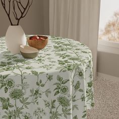 a table topped with a bowl of fruit next to a vase