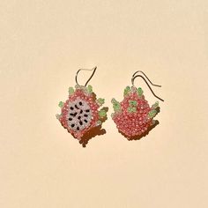 pair of earrings with pink and green beaded flowers on them sitting on a white surface