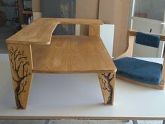 a wooden desk and chair sitting on top of a white table next to each other