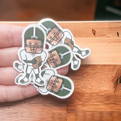 a hand holding a sticker with footballs on it and the image of an american football player