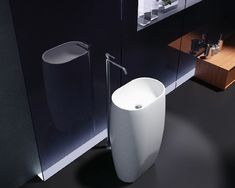 a modern bathroom with black walls and flooring, including a white sink in the corner