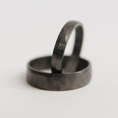 two wedding rings sitting next to each other on top of a white surface with no background