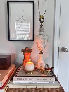 a stack of books sitting on top of a table next to a candle and pictures