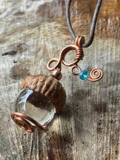 "This pendant is made using copper wire, fancifully looped through an acorn cap and swirling to hold a marble. It is accented with a Swarovski bicone bead. It's overall dimensions are 1.75\" long and 1\" at its widest point featuring a 16mm marble. It is on a leather cord tied with slip knots for an adjustable length.  We recommend removing this piece before showering or sleeping as it incorporates natural elements that should be treated with care." Mouse Warrior, Acorn Necklace, Cord Ties, Ice Queen, Natural Elements, Leather Cord, Copper Wire, Gemstone Pendant, Swirl