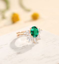 an emerald and diamond ring sitting on top of a table