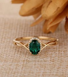 a ring with a green stone in the middle on a table next to some flowers