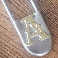 a close up of a metal padlock on a wooden surface with the letter a