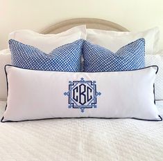 two blue and white pillows sitting on top of a bed