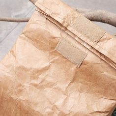 a brown paper bag sitting on top of a wooden table next to a tree branch