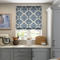 a kitchen with gray cabinets and blue patterned blinds