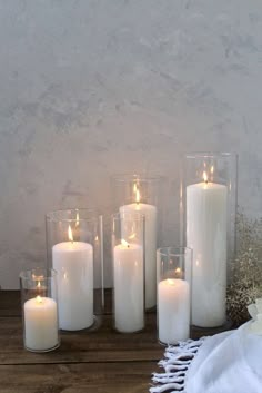 three white candles sitting on top of a wooden table