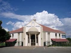 a large white building with a clock on the top of it's roof and fence around it