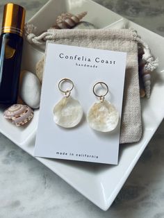 100% Handmade white jingle shells are arranged as beautiful drop earrings. They are very lightweight , great for all day wear. These nickel-free earrings feature gold-plated circle with stud back findings for comfort and simple aesthetic .  The shells for each pair are hand picked, and are meticulously assembled. These earrings have an organic and minimal look while still being very versatile. Would even make a beautiful addition to a beach bridal look. Please note,  each shell and by extension each pair have its own characteristics making them beautifully one of a kind . Bohemian White Mother Of Pearl Earrings, White Shell Jewelry Gift, Coastal Style White Shell-shaped Jewelry, Bohemian White Shell Earrings, White Shell Dangle Jewelry, White Coastal Shell Jewelry, White Coastal Style Shell-shaped Shell, White Mother Of Pearl Jewelry For Vacation, Handmade White Shell Earrings